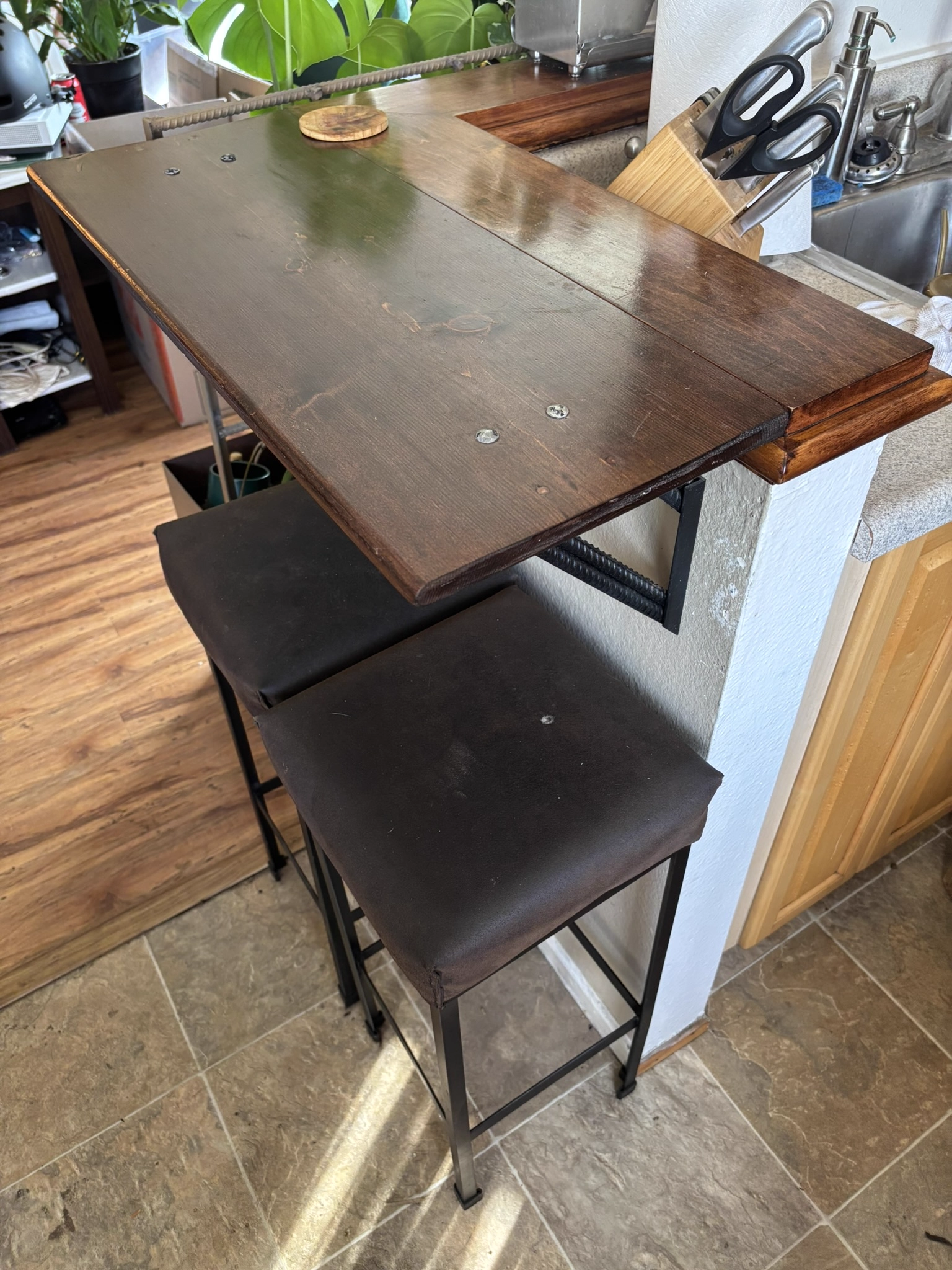 Finished dark wood bar top with metal brackets and stools